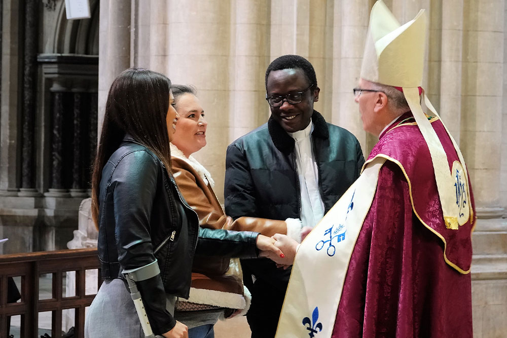 People meeting the bishop and shaking hands.