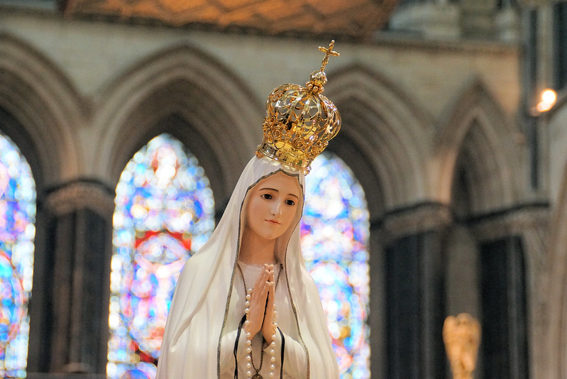 Statue of Mary, wearing crown, in prayer.