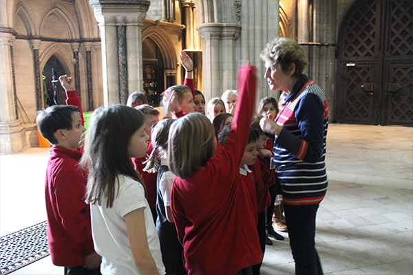 Woman talking, with school children gathered around.