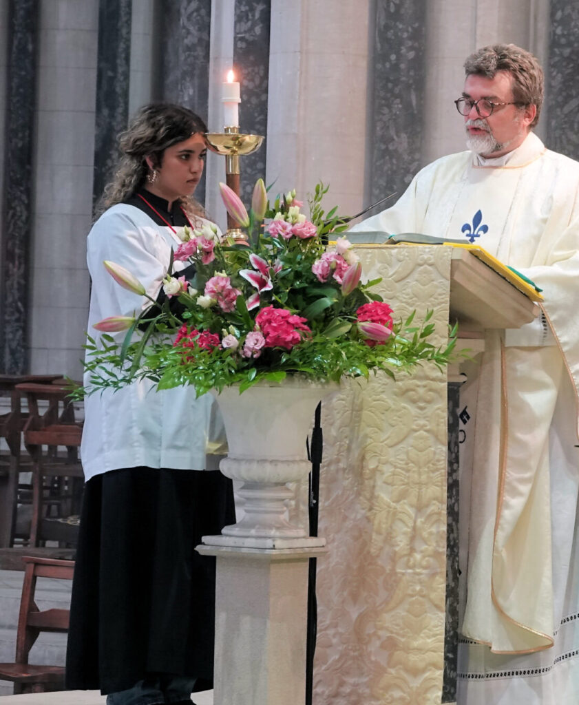 Alan Hodgson clergy at lectern with flowers and woman.