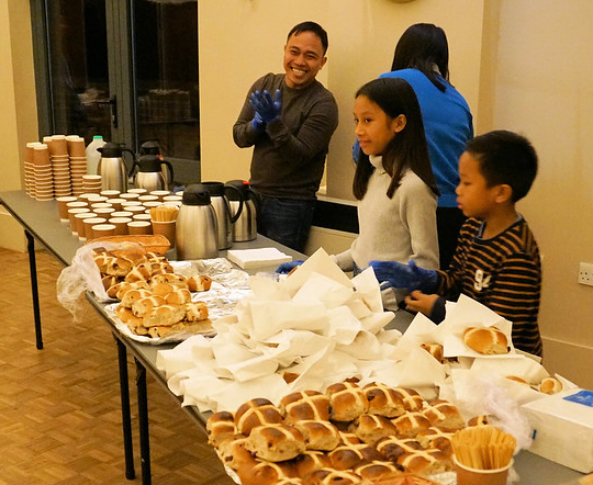 Children and father serving hot cross buns and tea.