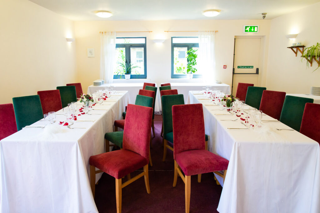 Wedding tables and red chairs decorating a hall