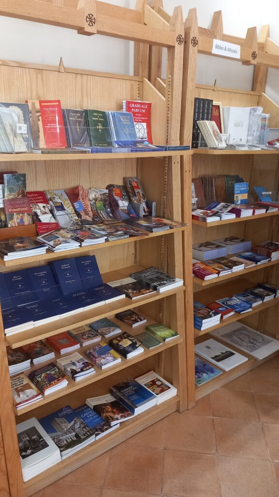 Wooden shop shelf containing books, notebooks and booklets.