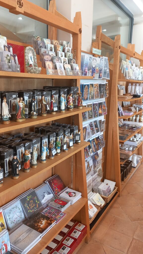 Wooden shelves containing religious figurines, trinkets and greetings cards.