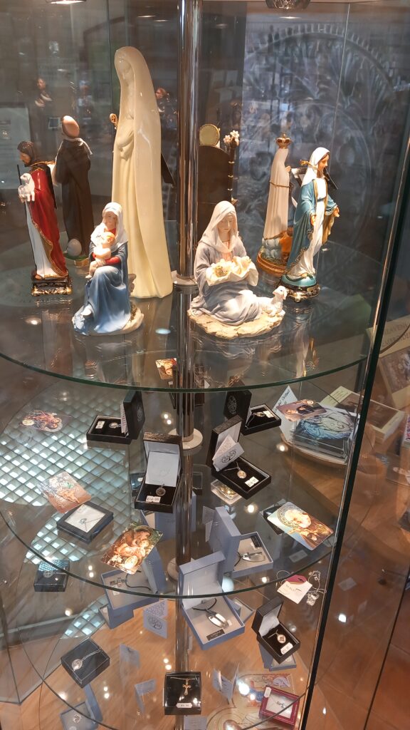 Glass shelf containing religious figurines and trinkets.