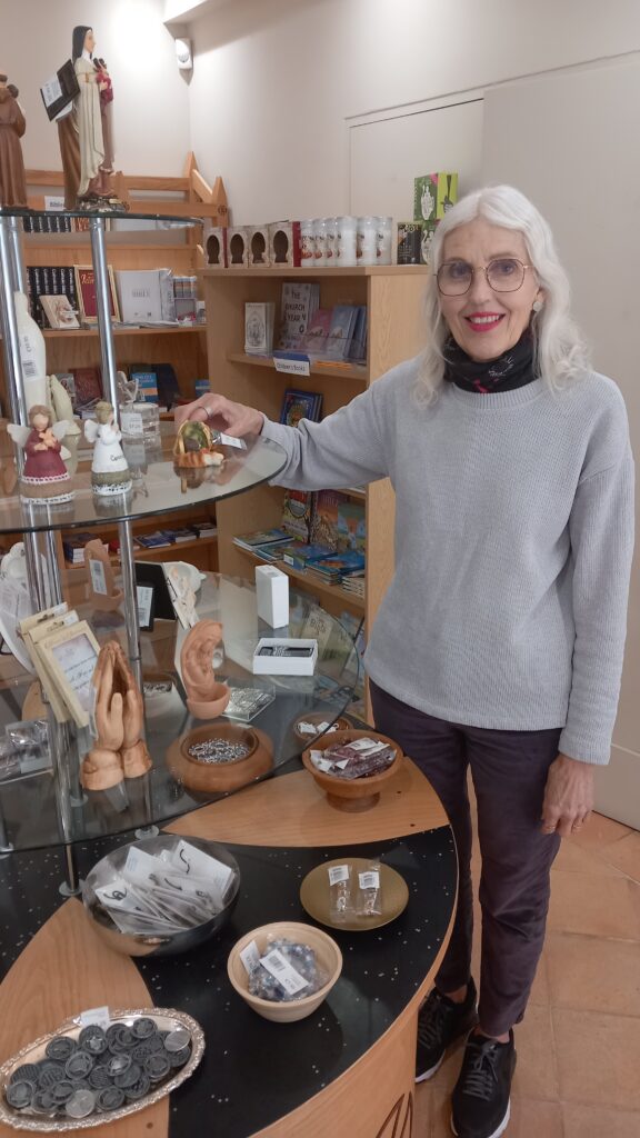 Lady standing near glass shelf containing religious items.